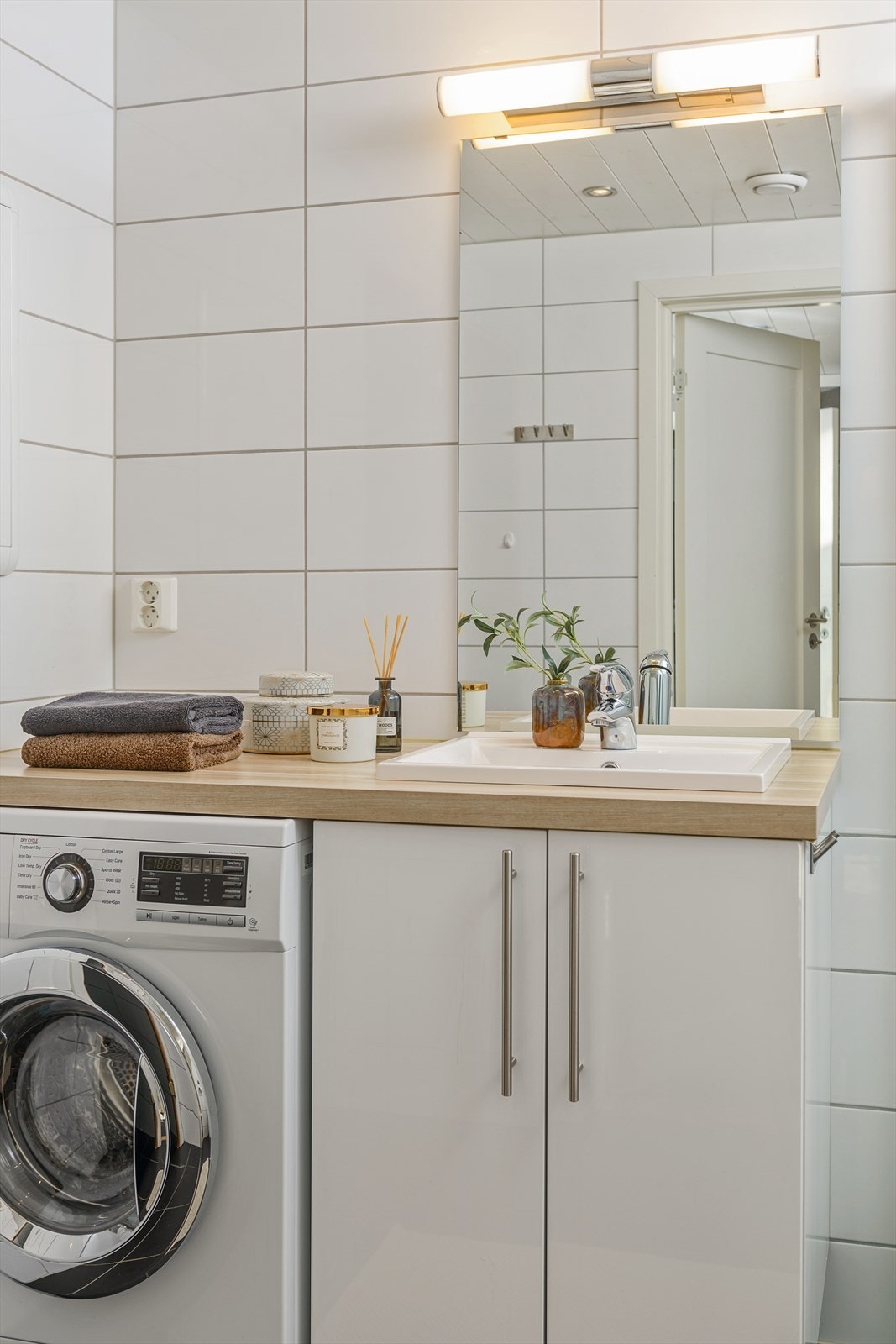 Badet er utstyrt med servant med underskap, speil med tilhørende belysning, dusjvegger og vegghengt toalett. Det er plass og opplegg for vaskemaskin. Galleribilde