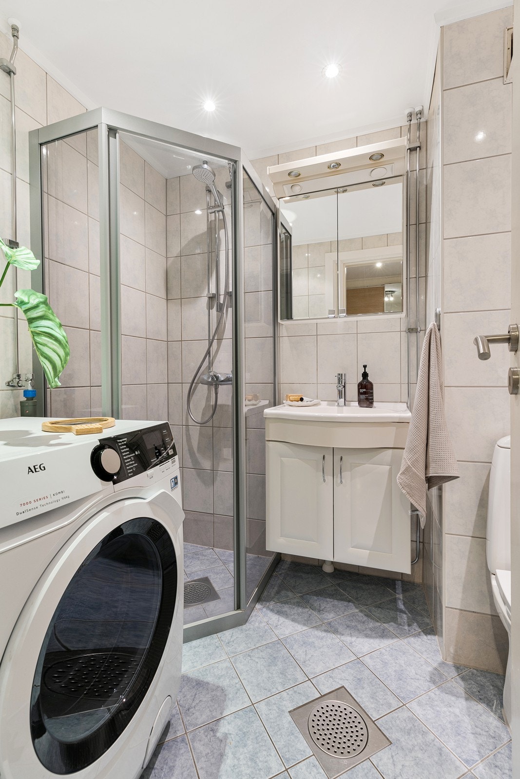 Leiligheten har et flislagt bad med dusjhjørne, toalett, servant med skap og opplegg til vaskemaskin. Galleribilde