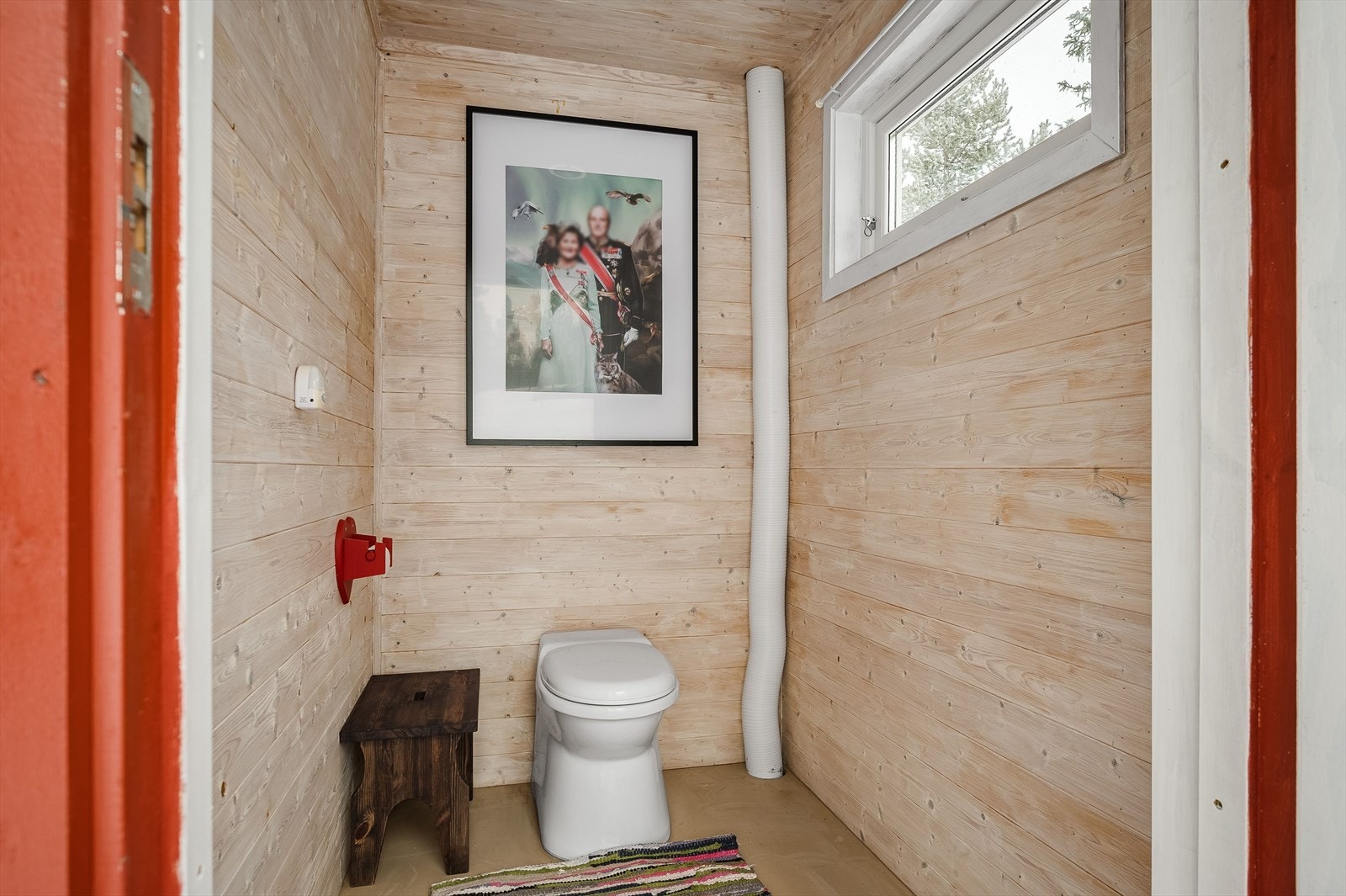 Toalettrommet har gulvflater med malte plater og panel i tak og vegger. Biodo. Galleribilde