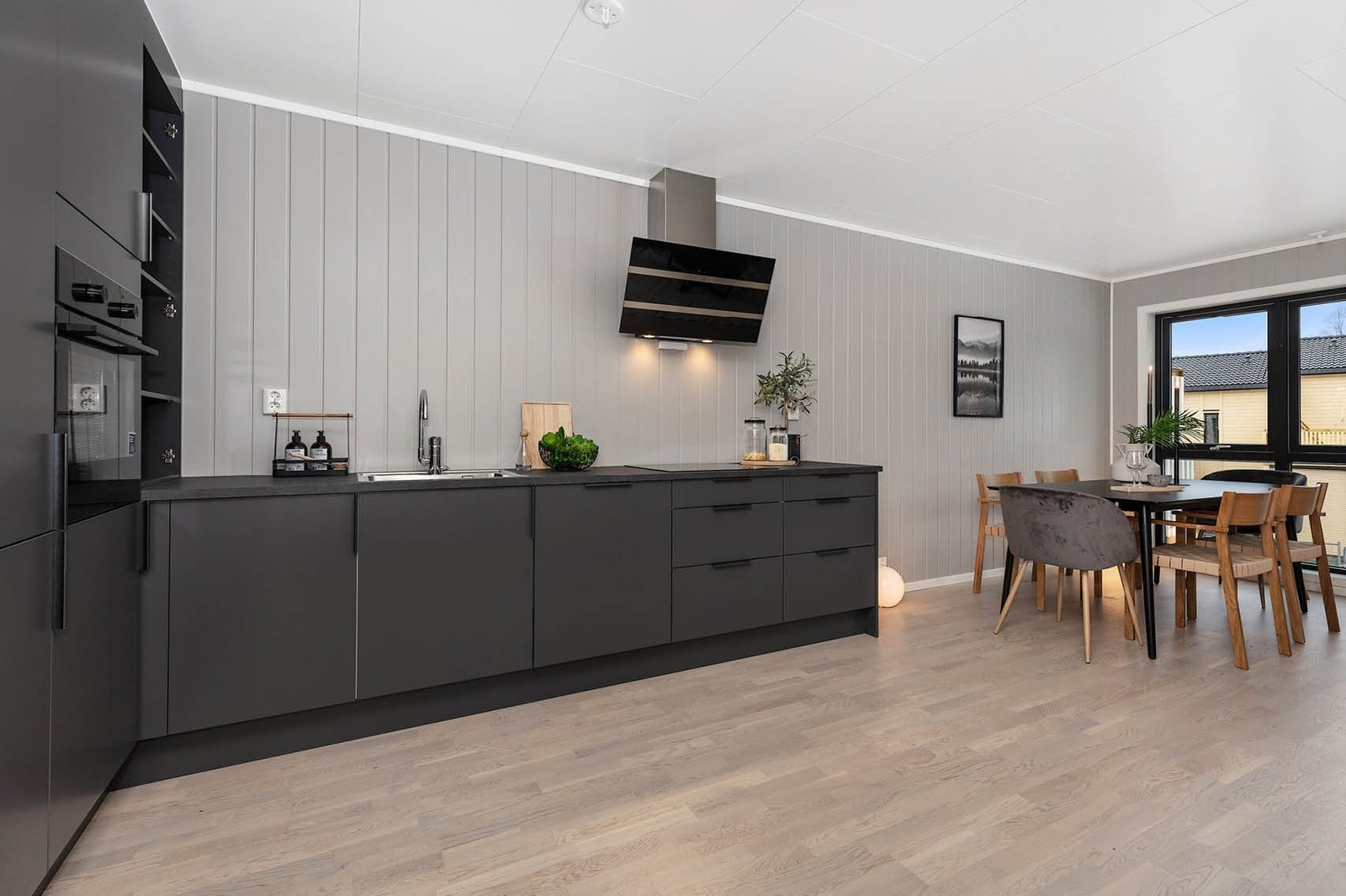 Lekkert stilrent kjøkken m. integrerte hvitevarer. Stekeovn i høyskap, platetopp med induksjon oppvaskmaskin og kombi kjøl/frys, samt moderne ventilator Galleribilde