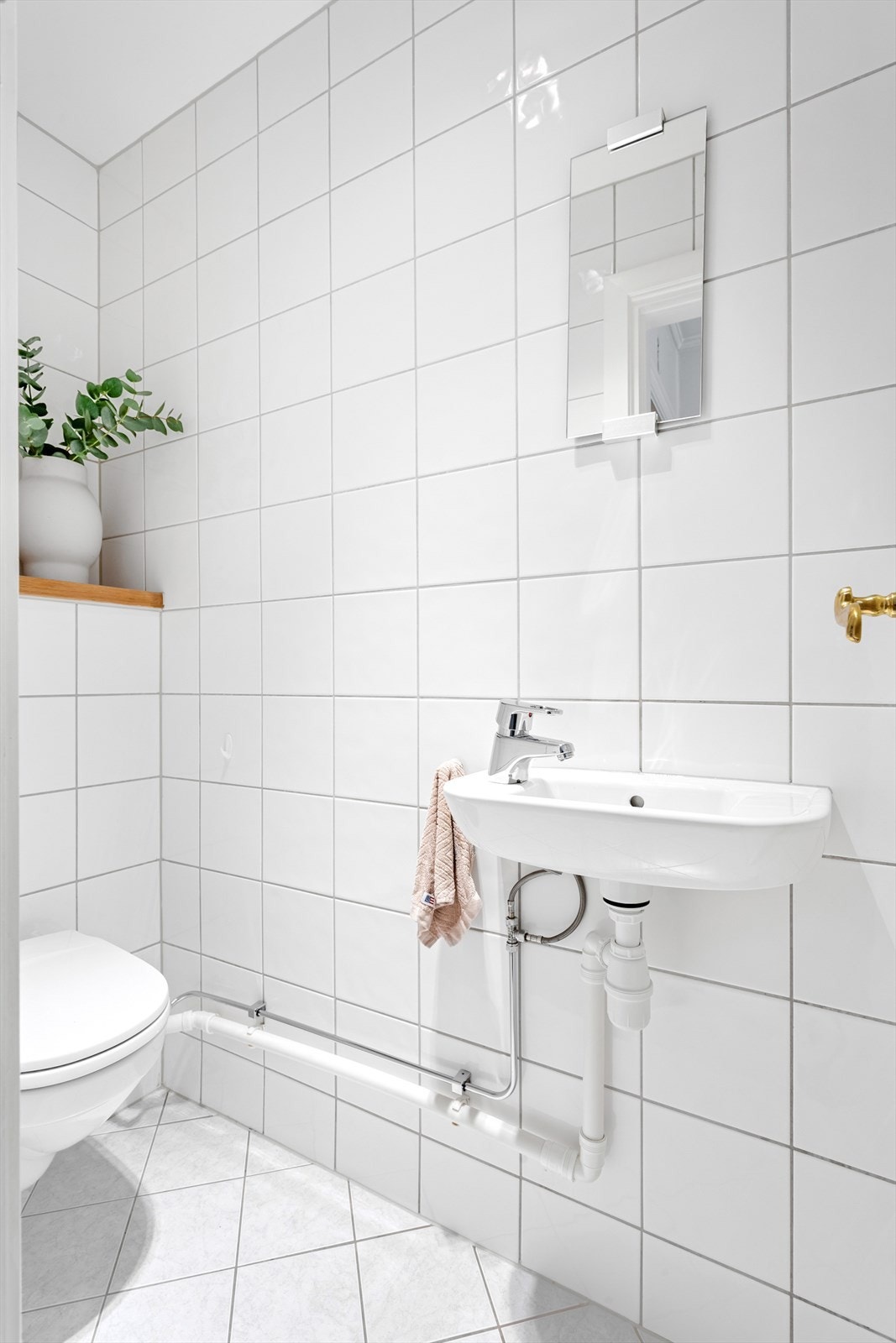 Praktisk toalettrom med flislagte vegger, malt himling og flislagt gulv med varmekabler. Galleribilde