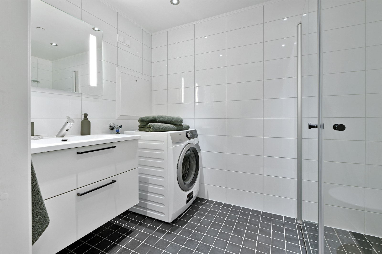 Bad i 1. etasje - flislagt gulv og vegger, malt himling - gulvvarme - downlights i himling - baderomsinnredning (servant med underskap og speil) - opplegg til vaskemaskin Galleribilde