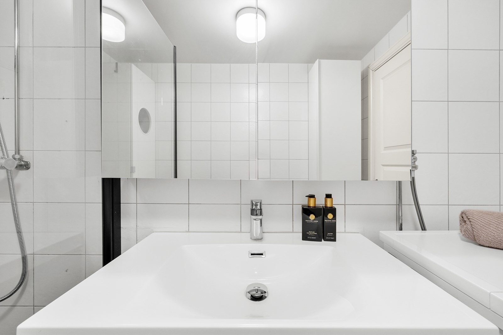 Badet er utstyrt med servant, overskap med speilfronter og integrert lys og dusjhjørne med glassvegger Galleribilde