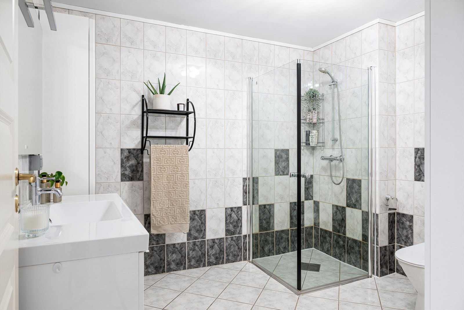 Badet er innredet med dusjnisje med glassvegger, toalett, høyskap og vask i seksjon. Galleribilde