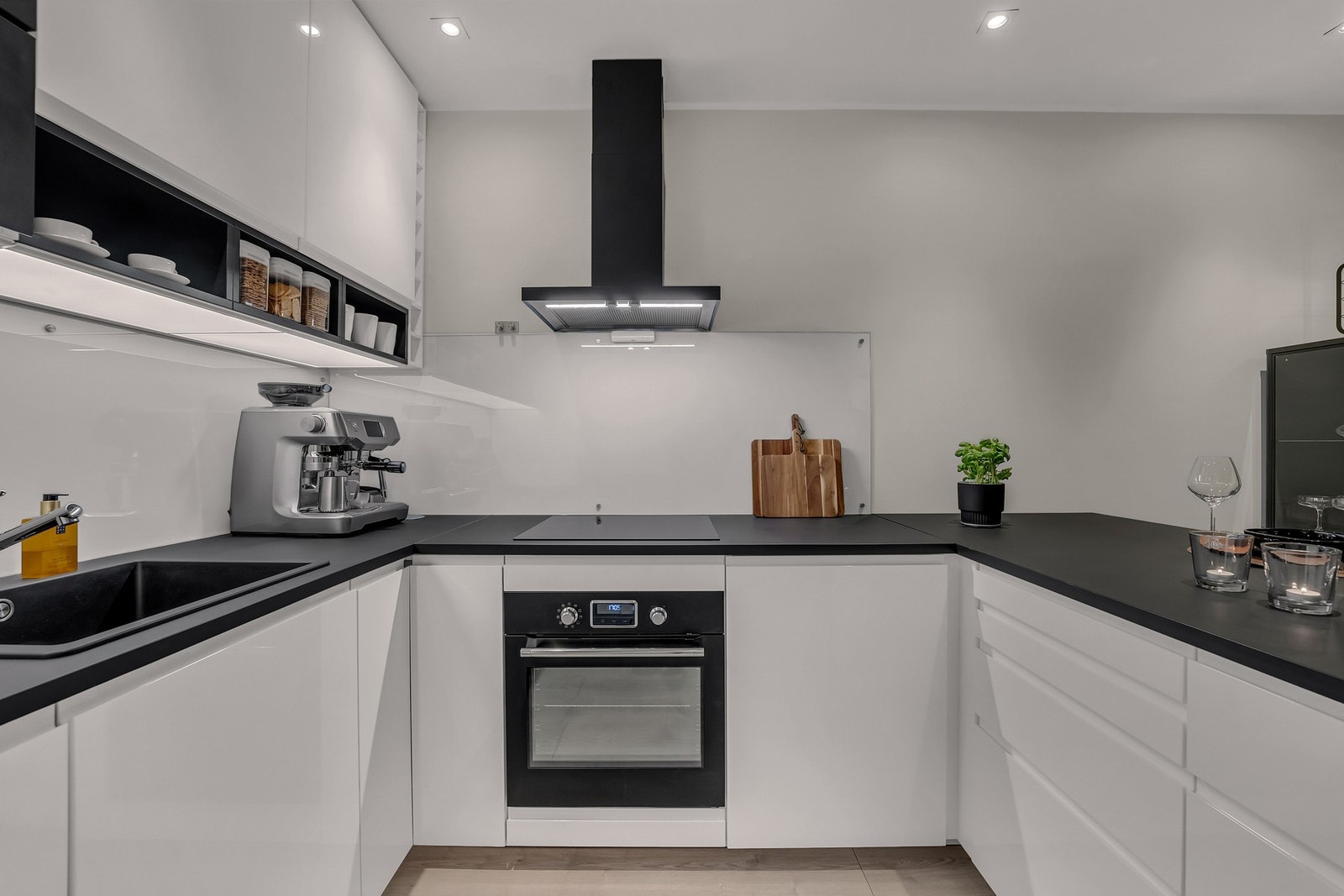Tidsriktig og moderne kjøkkeninnredning fra 2020 med hvite, glatte fronter og sort benkeplate. Galleribilde