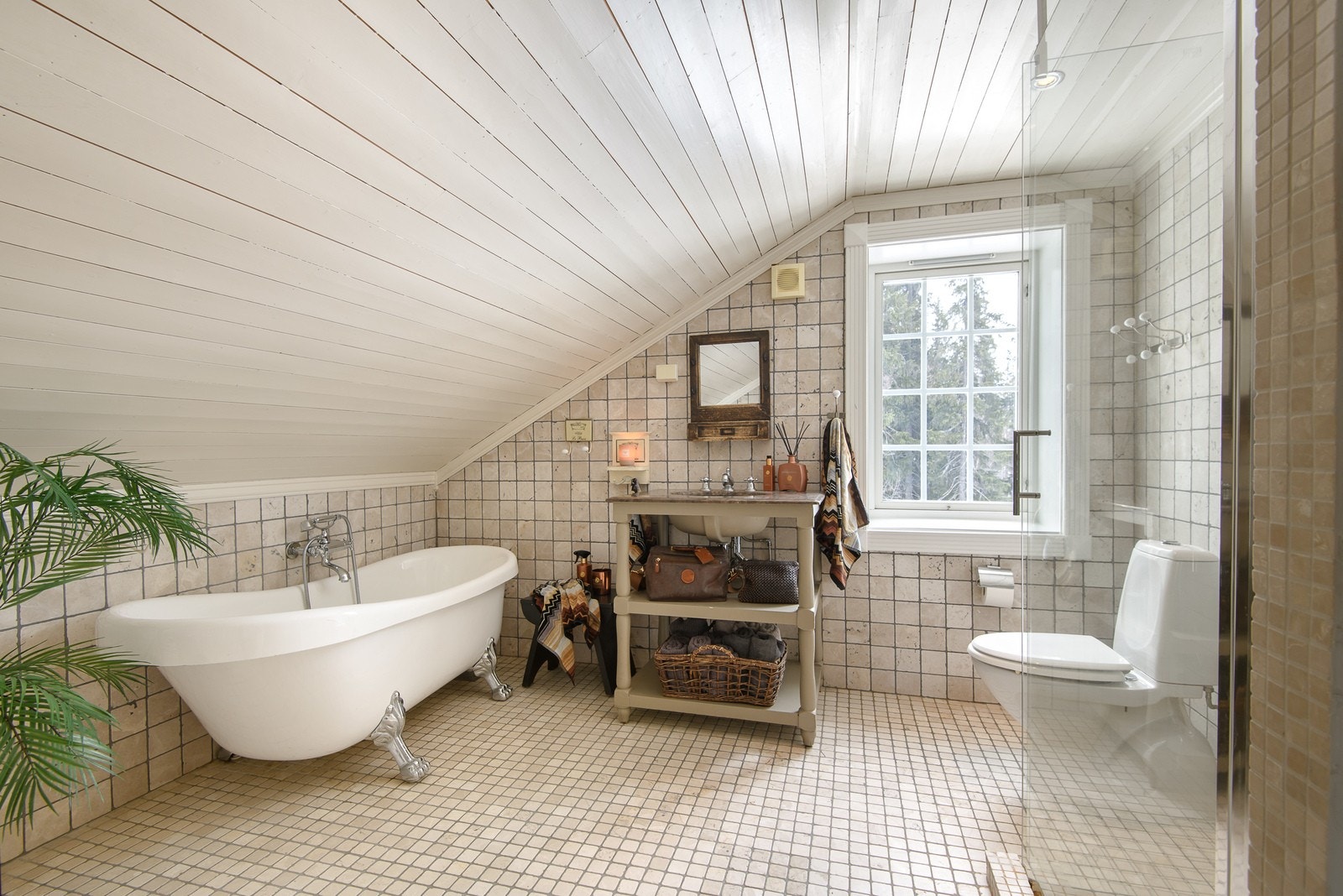 Flislagt baderom på loftsplanet, som innehar toalett, badekar, dusjhjørne og baderomsinnredning. Galleribilde