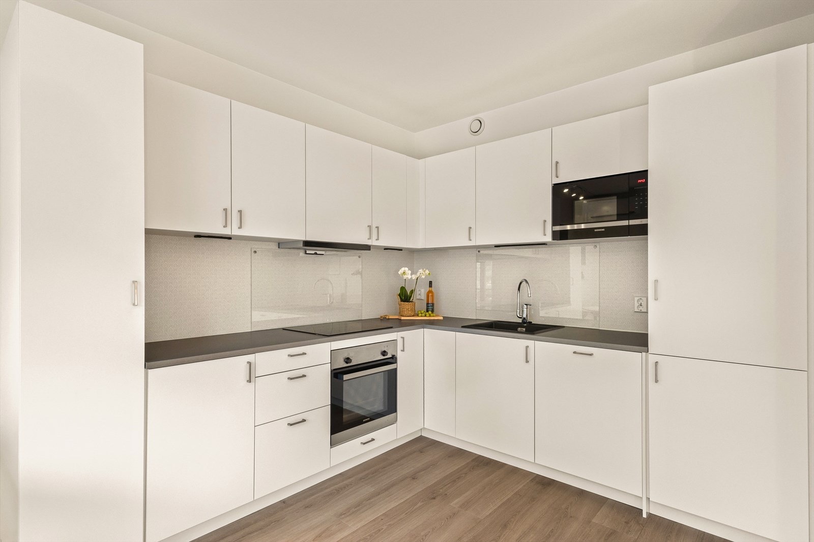 Kjøkkeninnredningen har en stilren utførelse med hvite, glatte fronter og laminert benkeplate. Galleribilde