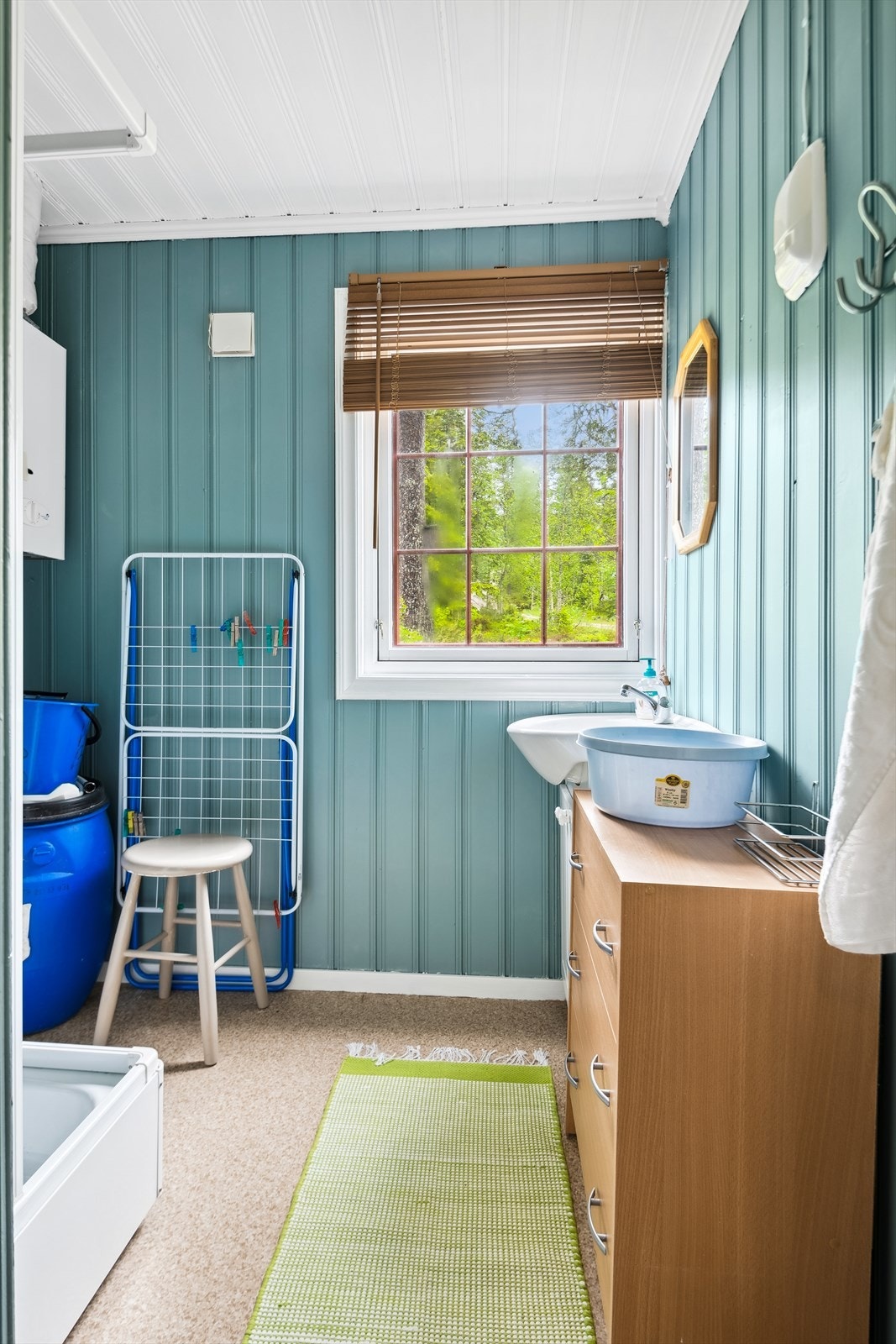 Et trivelig bad med malt panel på vegger og tak og belegg på gulvet. Dusjkabinett og skap med vask Galleribilde