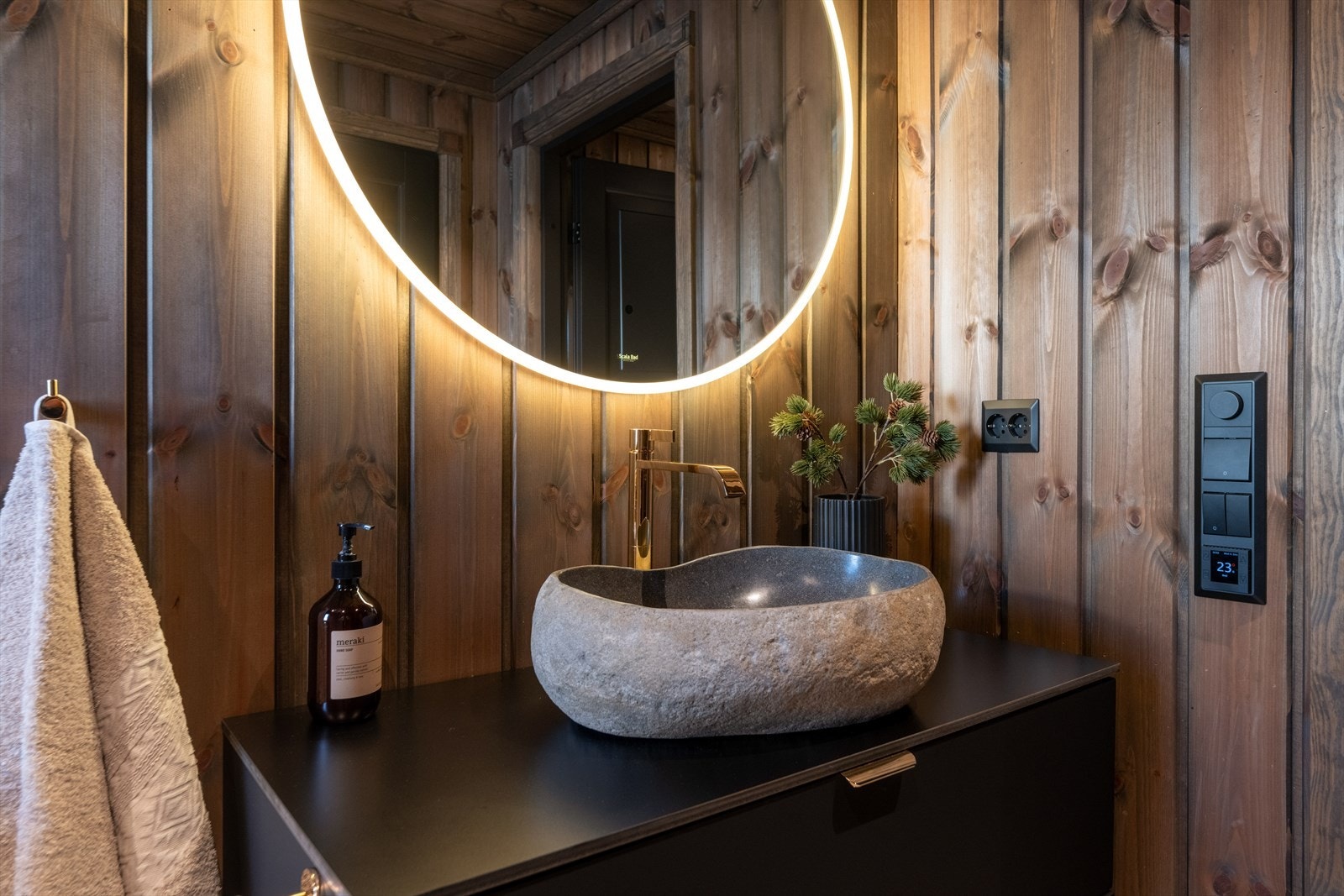 Baderomsmøblementet er veggheng med to underskuffer og en tøff vaskebolle på benkflate. Stor speilflate over vask med integrert belysning. Gulvmontert toalett. Galleribilde