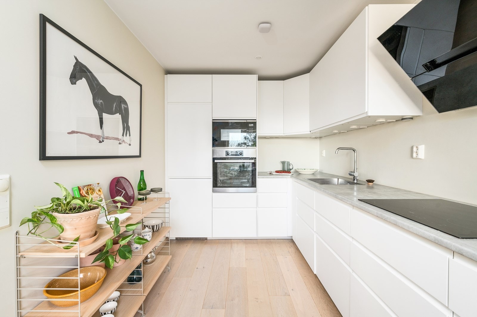 Stilrent kjøkken fra 2019 med downlights i himling, lyse kjøkkenfronter og laminat benkeplate med en mørkere fargetone som gir en fin kontrast. Galleribilde