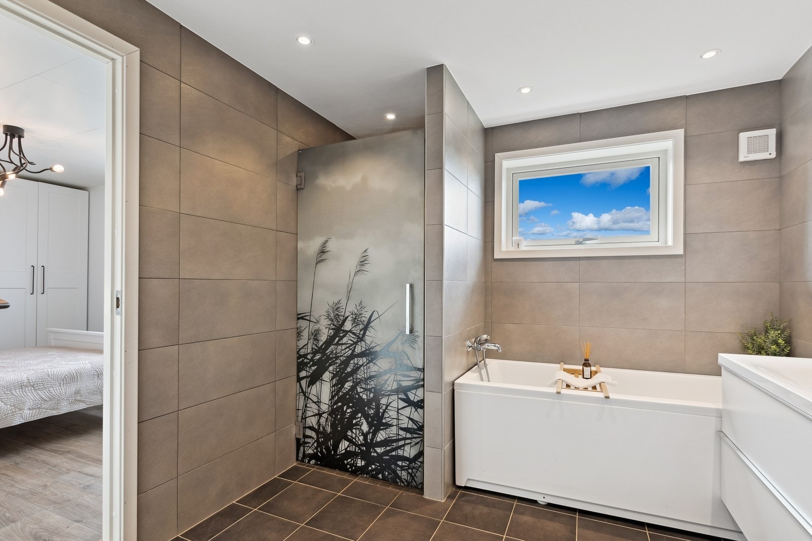 Rommet har lys innredning, speil med belysning, høyskap, veggmontert toalett, dusjhjørne og deilig badekar. Galleribilde