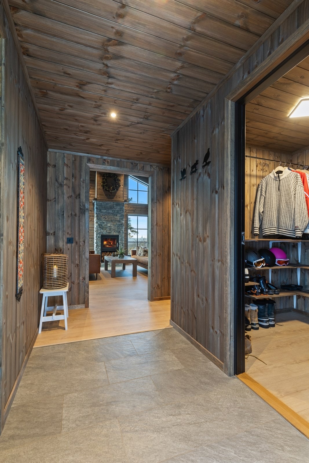 Romslig gang/entré med innvendig bod og toalett-/vaskerom rett innenfor inngangsdøren. Det er flislagt gulv med varme, behandlet panel på vegg og i himling, med downlights. Galleribilde