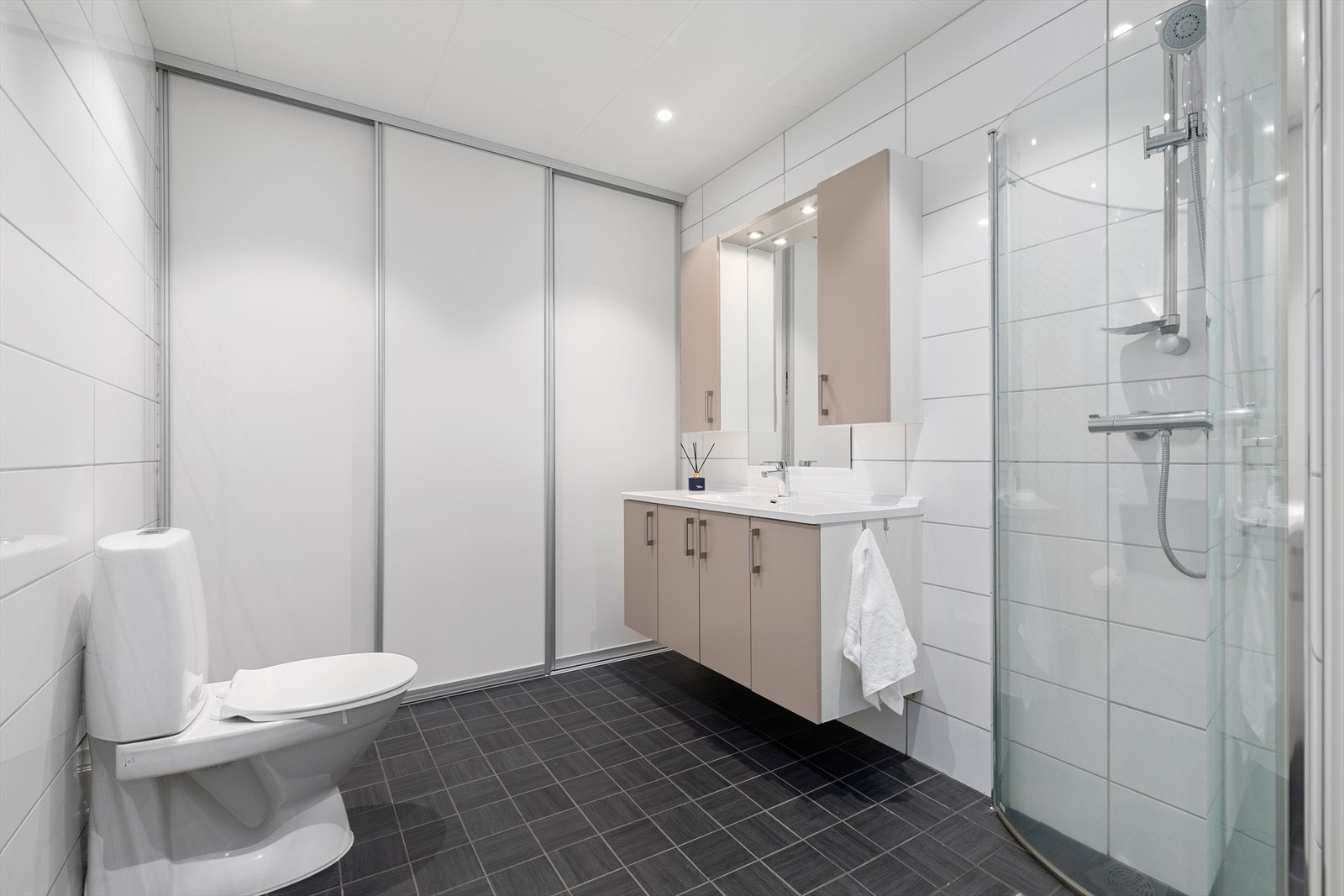 Kombinert baderom/vaskerom, vaskeromdel skjult bak skyvedør Galleribilde