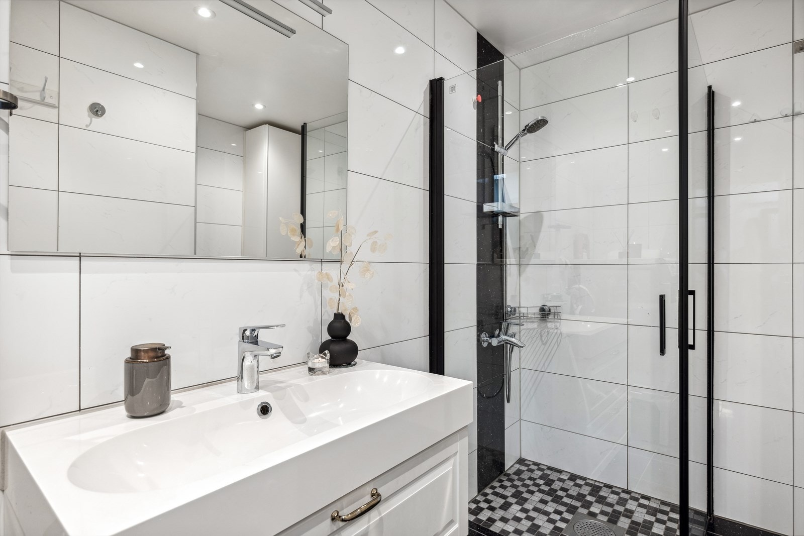 Badet er romslig og fint med lyse, moderne fliser og lekre detaljer Galleribilde