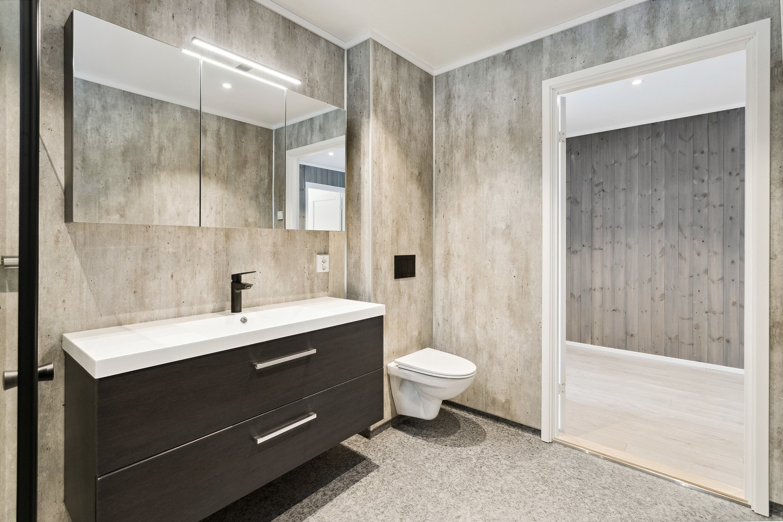 Lekkert bad med baderomsinnredning, speilskap og vegghengt toalett Galleribilde