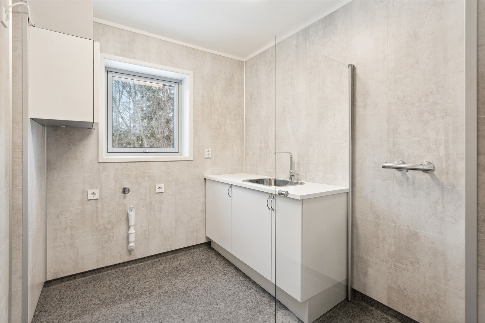 Praktisk vaskerom med skyllekum i innredning og opplegg for vaskemaskin Galleribilde