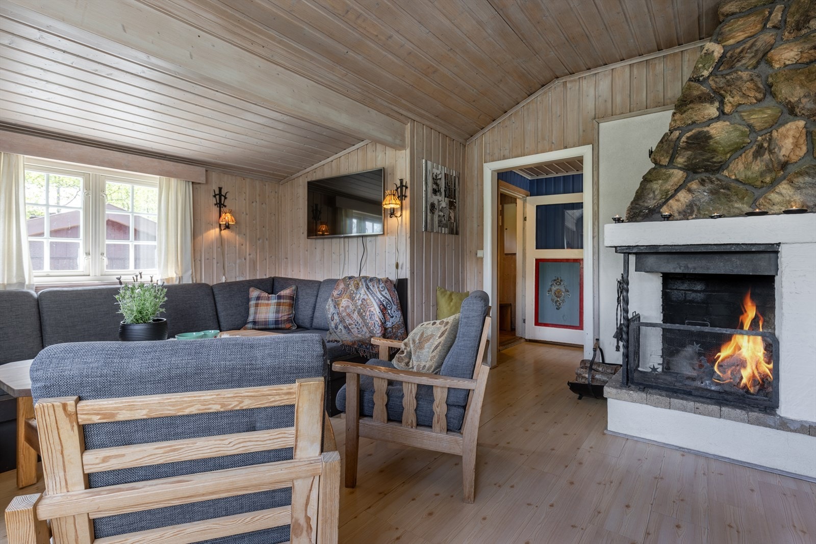 Hytta har en sosial og hyggelig planløsning. Her fra stue og spisestue med peis sentralt plassert. Galleribilde