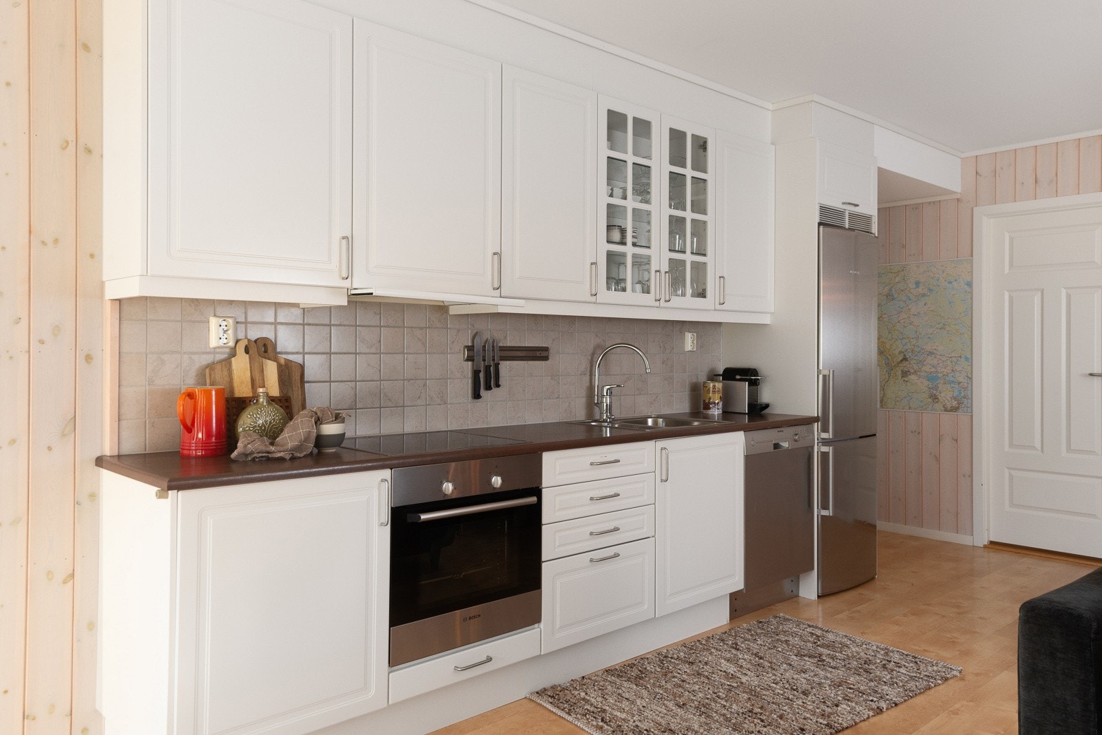 Kjøkkeninnredningen har profilerte fronter og ett skap med speilfronter. Benkeplate i laminat. Det er fliser mellom over- og underskap. Galleribilde