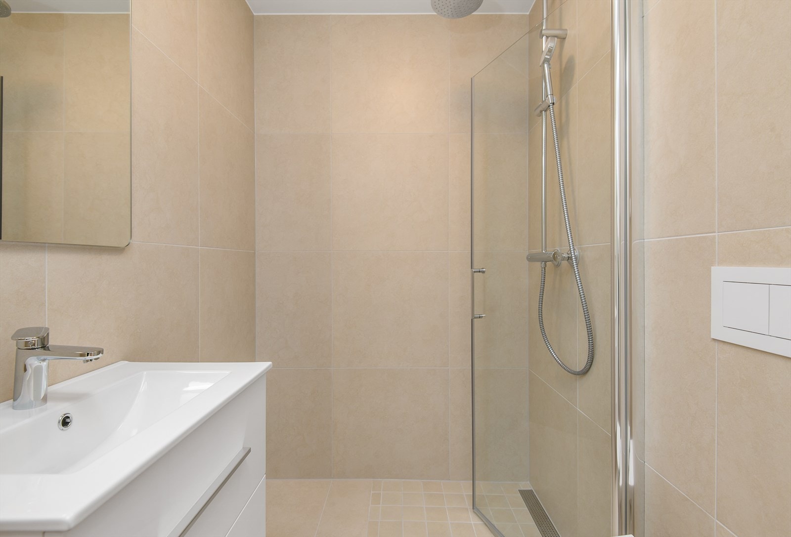 Baderommet har innredning bestående av servant med underskuffer i hvit utførelse, speilskap med lysarmatur, vegghengt wc med skjult sisterne samt dusjhjørne med innfellbar dusjvegg. Galleribilde