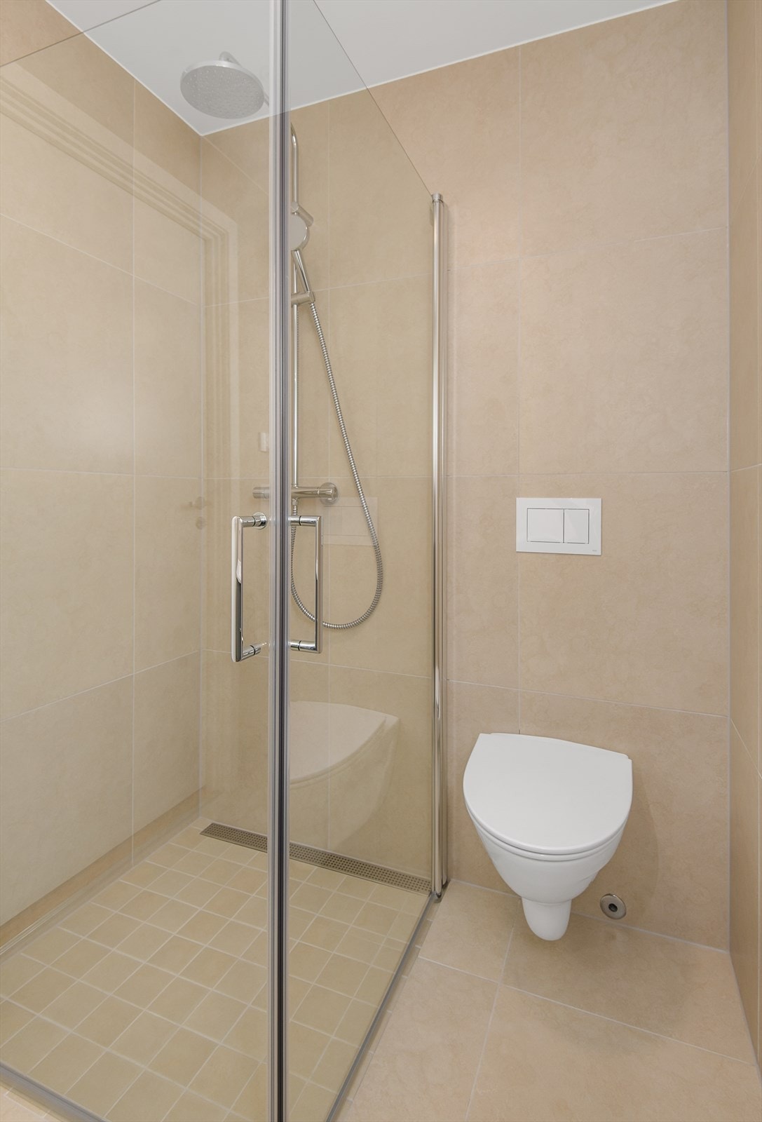 Det minste badet har vegghengt wc, romslig dusjhjørne med innfellbare dusjvegger. Flislagt i format 60x60 med fargen "Ivory". Galleribilde
