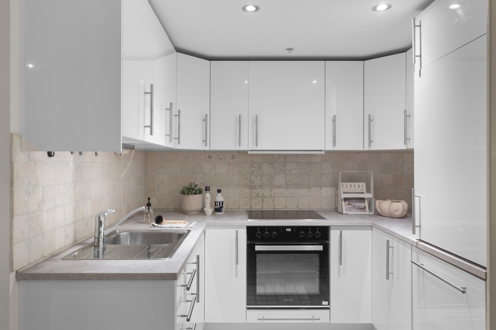 Kjøkkeninnredning med glatte fronter og foliert benkeplate. Kjøkkenet er utstyrt med platetopp, kum med ettgreps blandebatteri, ventilator, kjøleskap, ovn og oppvaskmaskin. Galleribilde