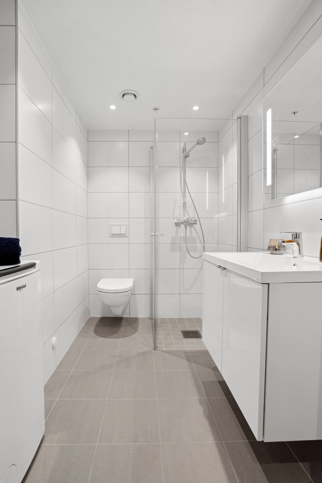 Baderomsinnredning bestående av benkeskap med glatte fronter i høyglanset utførelse. Speil med belysning over servant. Opplegg for vaskemaskin. Galleribilde