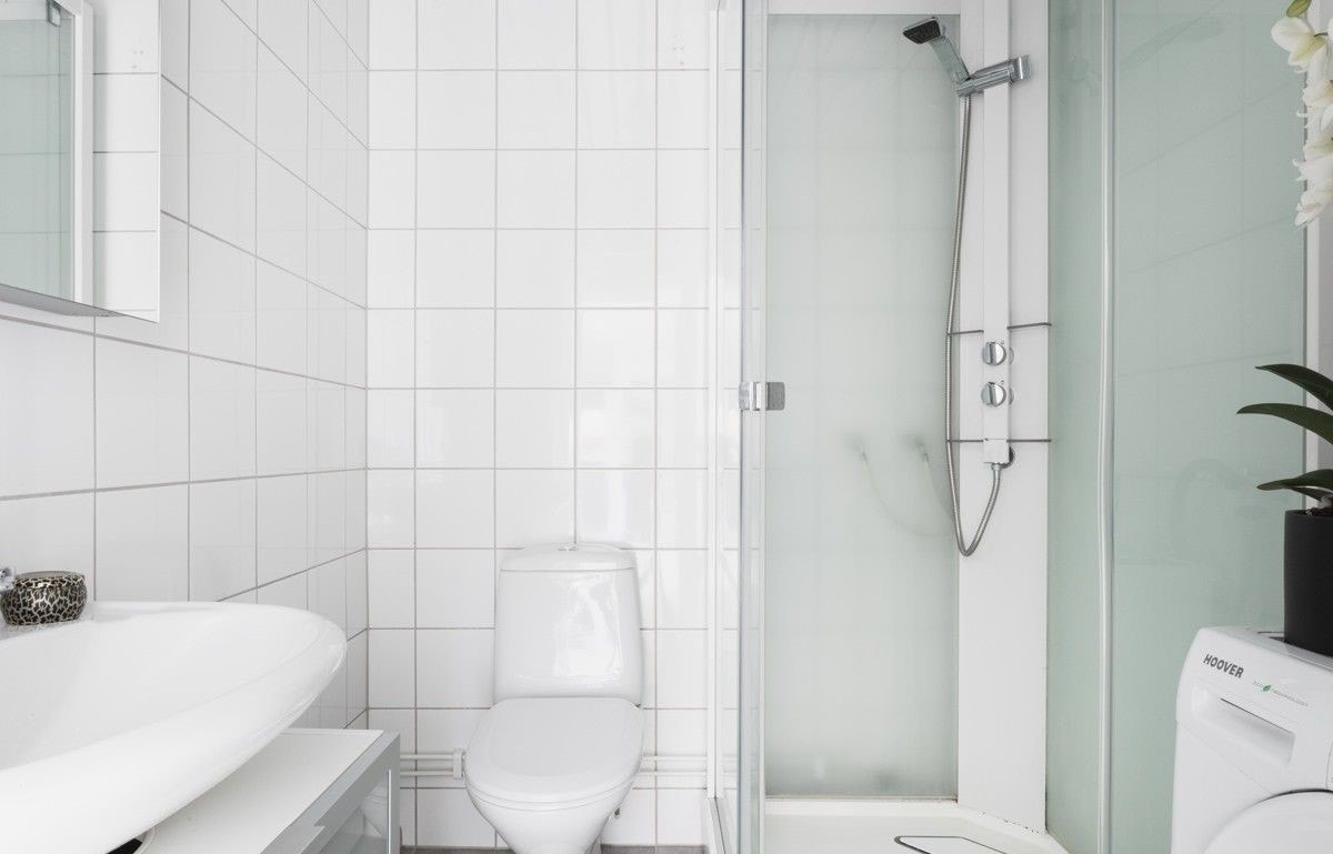 Flislagt baderom med dusj og opplegg for vaskemaskin. Galleribilde