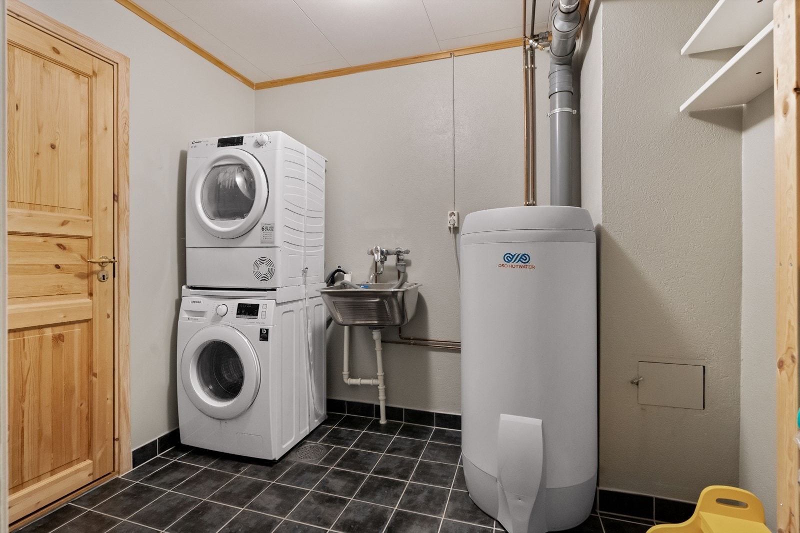 Vegg i vegg med badet ligger et praktisk vaskerom. Rommet har flislagt gulv, og er utstyrt med utslagsvask i rustfritt stål, vaskesøyle og plassbygde oppbevaringshyller. I rommet står også varmtvannsbereder. Galleribilde