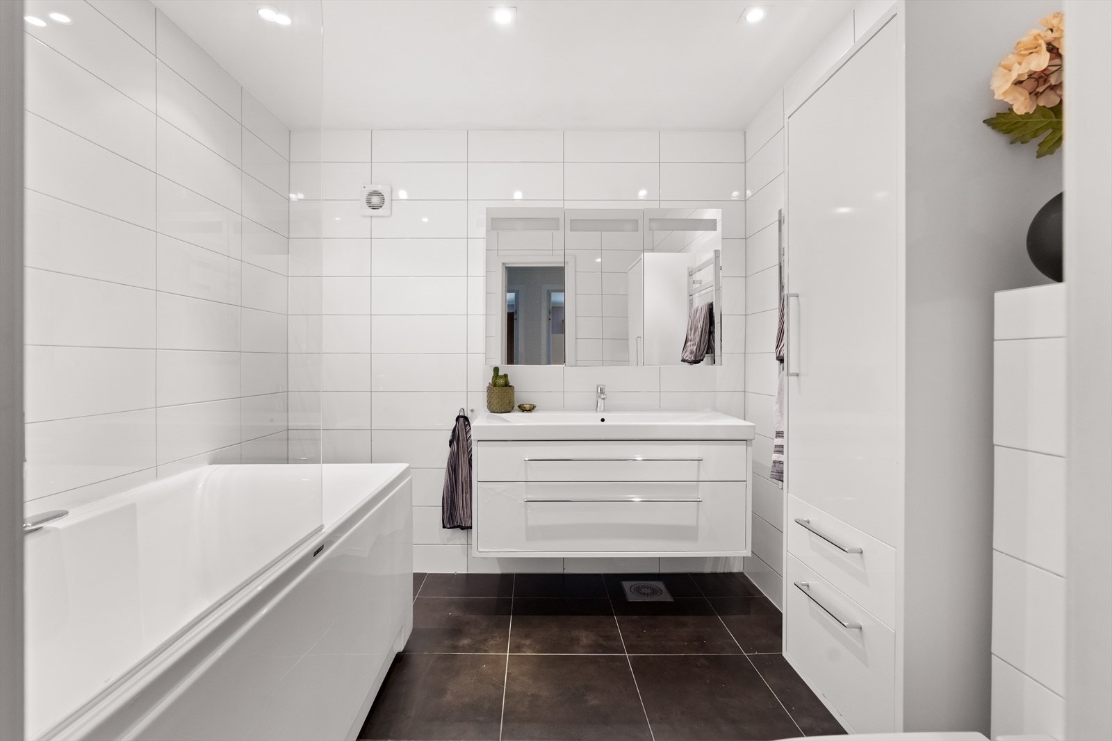 Også underetasjen har et flislagt baderom. Rommet er innredet med servantskap med glatte, folierte fronter og heldekkende servant, samt et speilskap med lys på veggen over servanten. Galleribilde