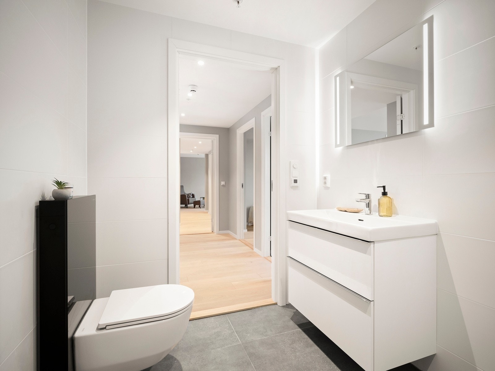 Badet består av vegghengt wc, servant med underskuffer og speil over servant, dusj med dusjdører av herdet glass. Galleribilde