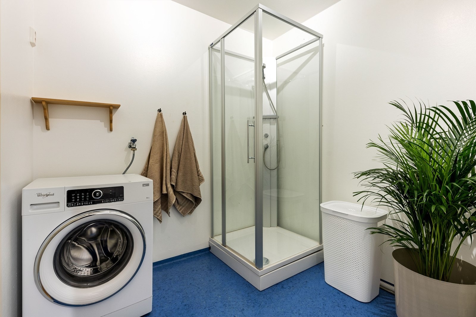 Badet er innredet med servant over innredning, toalett, dusjkabinett og opplegg til vaskemaskin Galleribilde