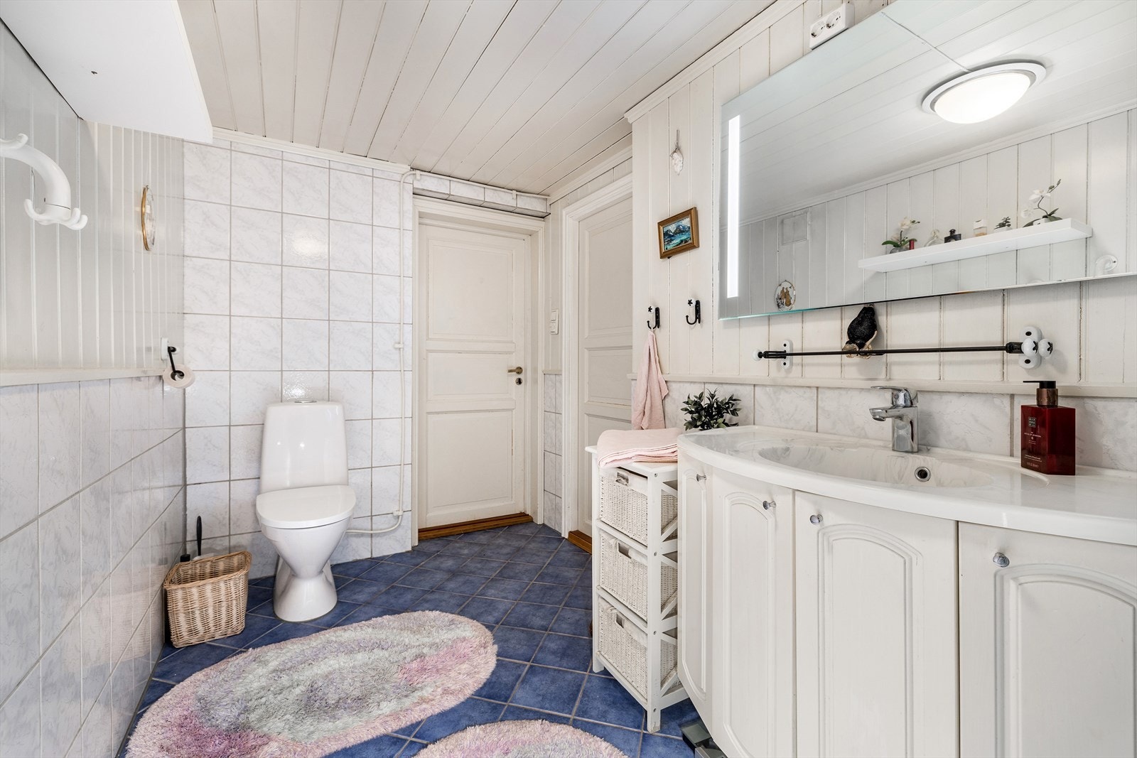 Badet er innredet med servant, speil med belysning, gulvstående toalett og dusjnisje. Galleribilde