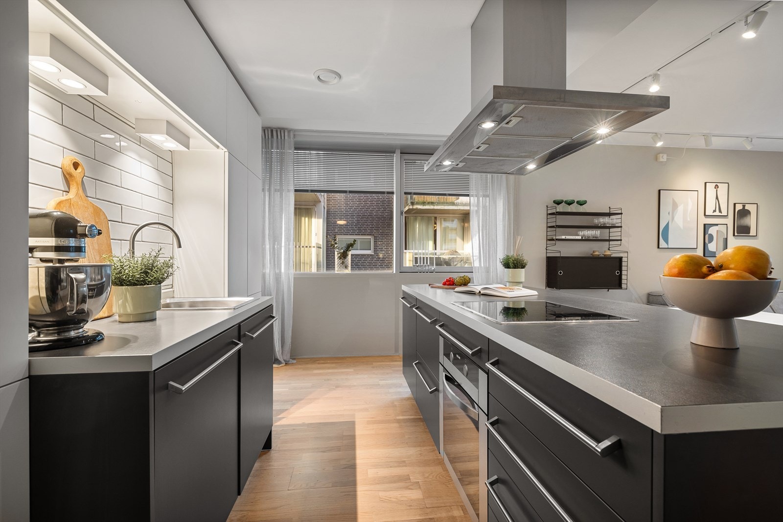 Kjøkkeninnredning fra 2005 med glatte fronter med stålhåndtak, fliser på vegg over kjøkkenbenk og benkeplate i laminat. Galleribilde