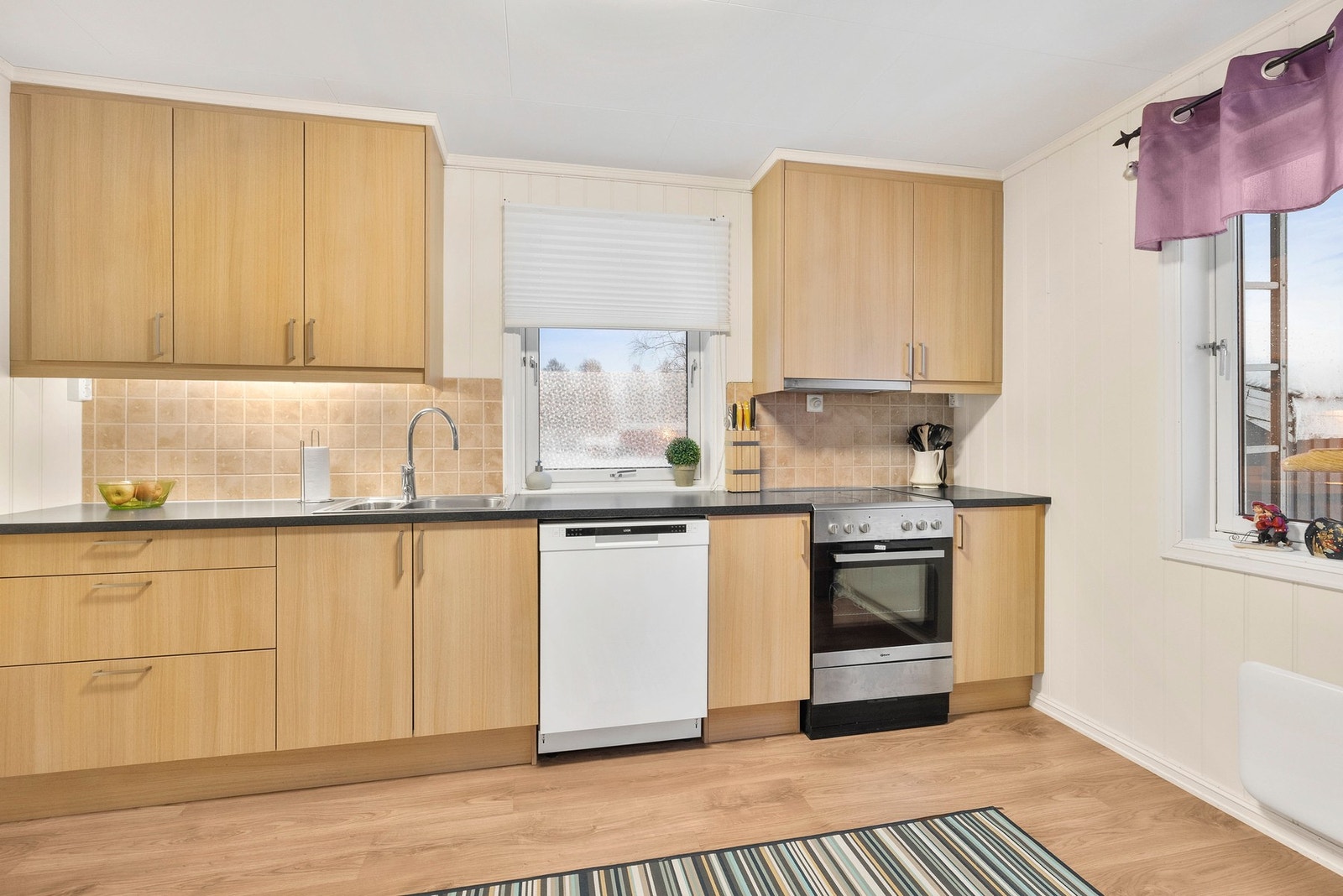 Kjøkken fra 2012 innredet med glatte folierte fronter og benkeplate av laminat med nedfelt servant Galleribilde