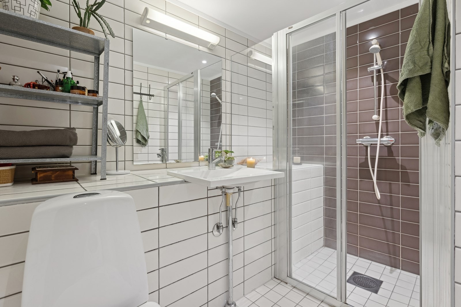 Badet disponerer vegghengt speil med overhengt lampe, downlight i himling. Badet har en stor karm til oppbevaring av toalettsaker, håndkler eller sminke. Galleribilde