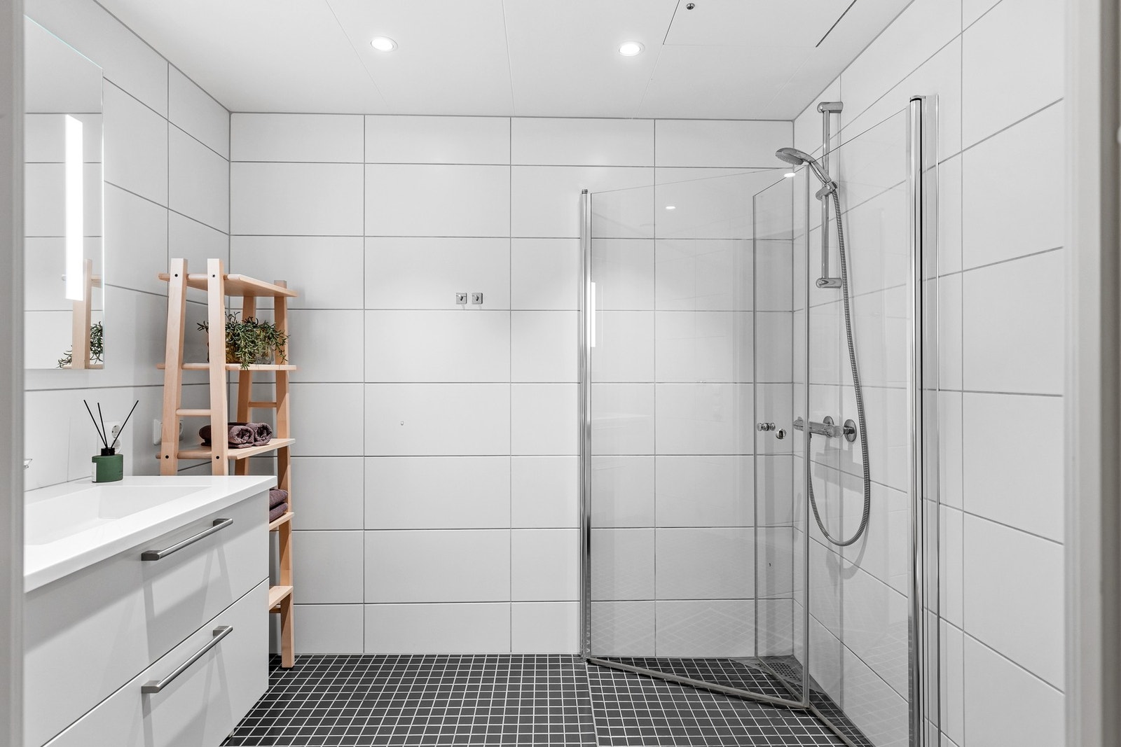 Innbydende flislagt bad med hvite plater i himling. Baderomsgulvet har elektriske varmekabler. Galleribilde