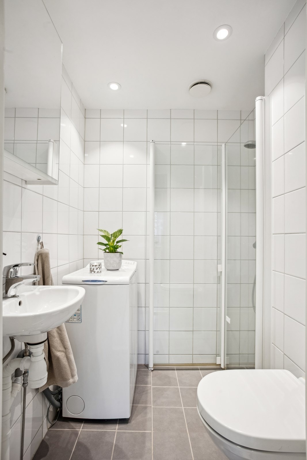 Badet er innredet med: Vegghengt servant. Speilskap på vegg over servant. Veggmontert klosett. Nedsenket dusjhjørne med rette svingdører, sluk og termostatstyrt blandebatteri. Samt opplegg for vaskemaskin. Galleribilde