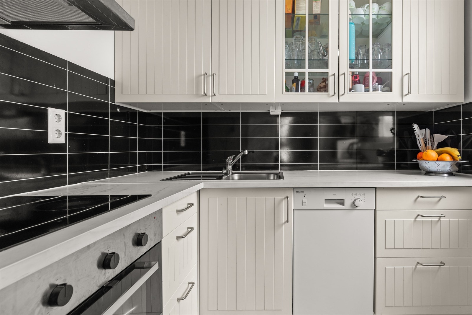 Kjøkkeninnredning består av hvite, profilerte fronter og laminat benkeplate med nedfelt vaskekum. Galleribilde