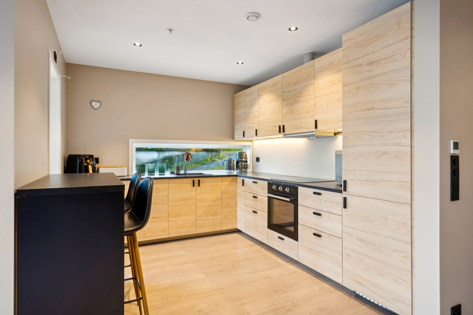 Kjøkkeninnredning med slette trefargede fronter og laminat benkeplate. Galleribilde