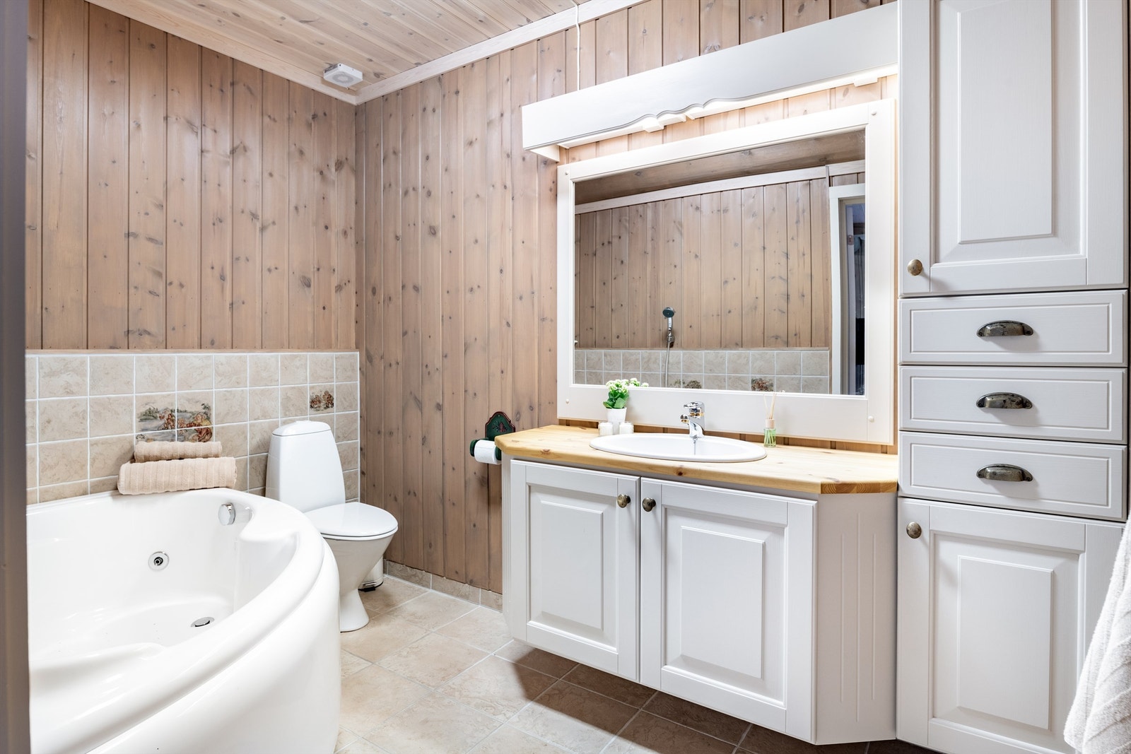 Bad 2 har raust med innredning, hjørne-boblekar , wc og vask med stort speil over Galleribilde