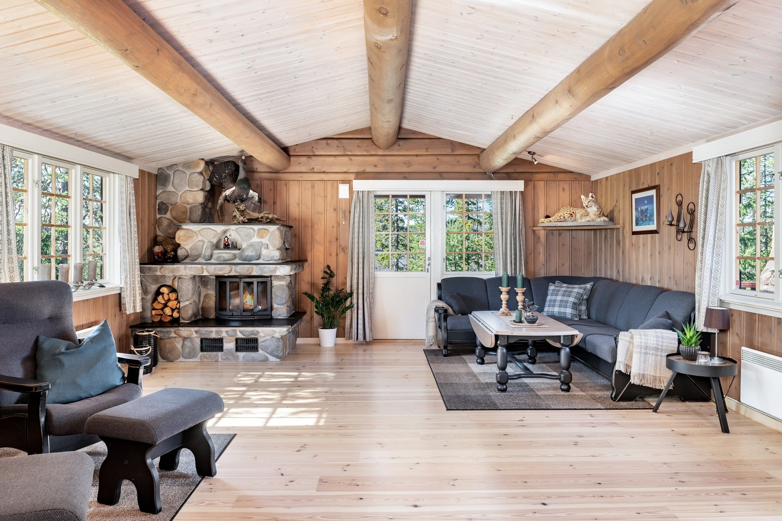 Velkommen inn i en meget koselig stue med god takhøyde og synlige takåser. Vinduer på 3 vegger og utgang til terrassen. Peis forblendet med naturstein Galleribilde
