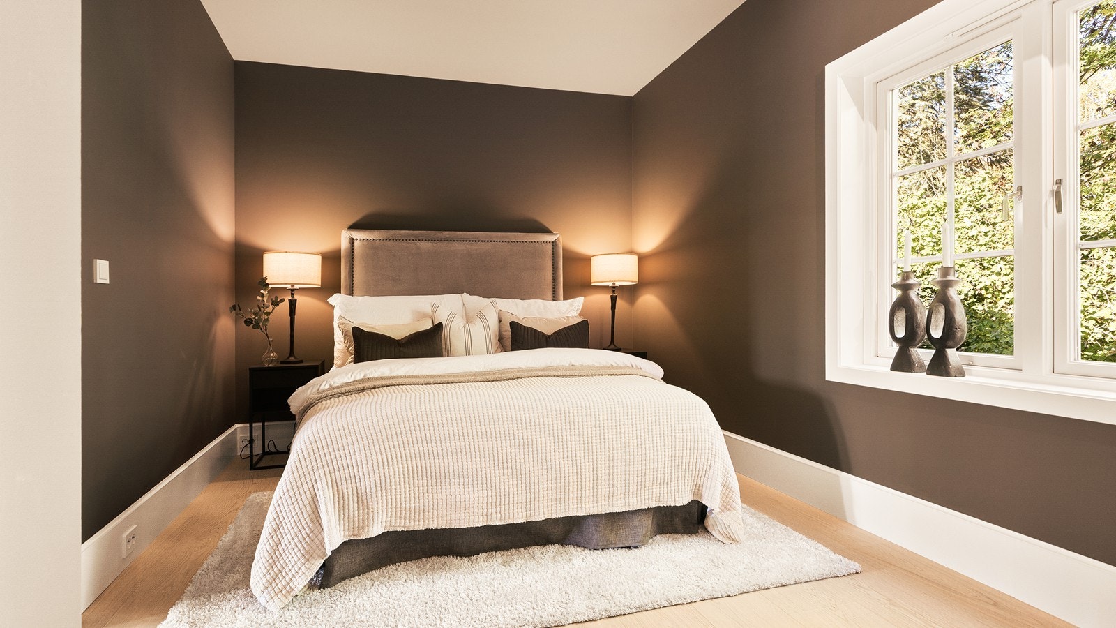 Stort soverom med 1-stavs parkett og veggoverflater malt i varme fargetoner Galleribilde