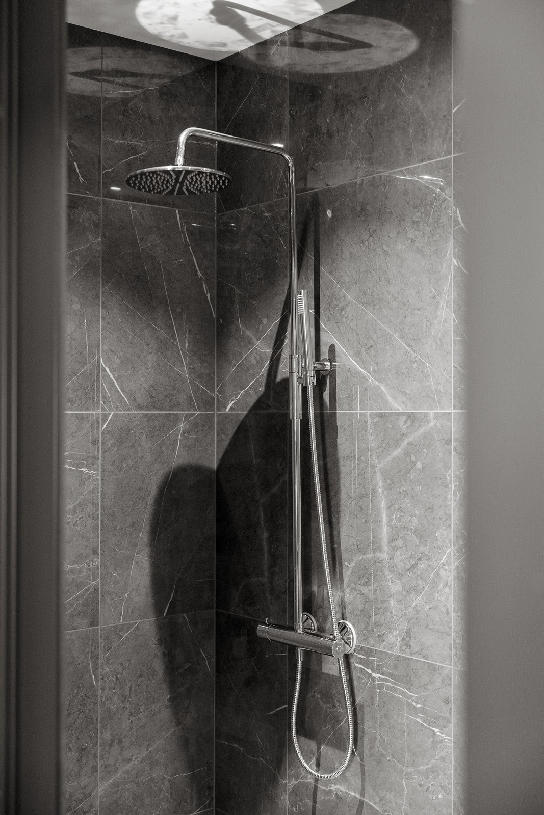 Nedsenket dusjsone i egen nisje. Dusjsonen har mosaikkflis på gulv, designsluk og regnfallsdusj Galleribilde