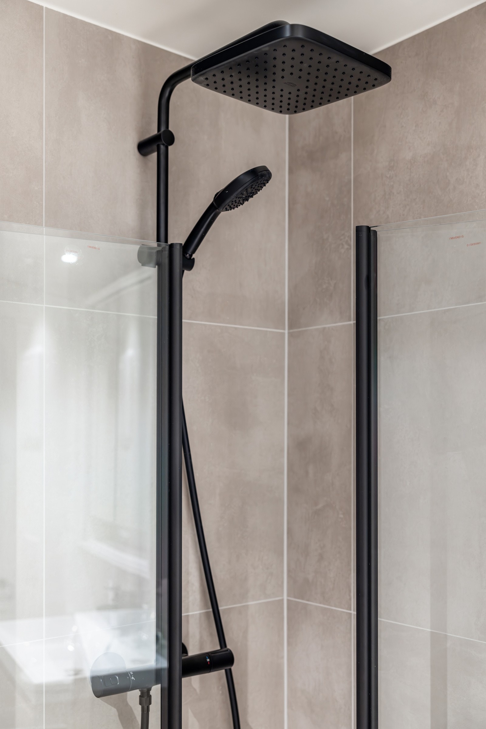 Sorte detaljer på armatur, inkludert regndusj, gir badet et stilrent uttrykk. Galleribilde