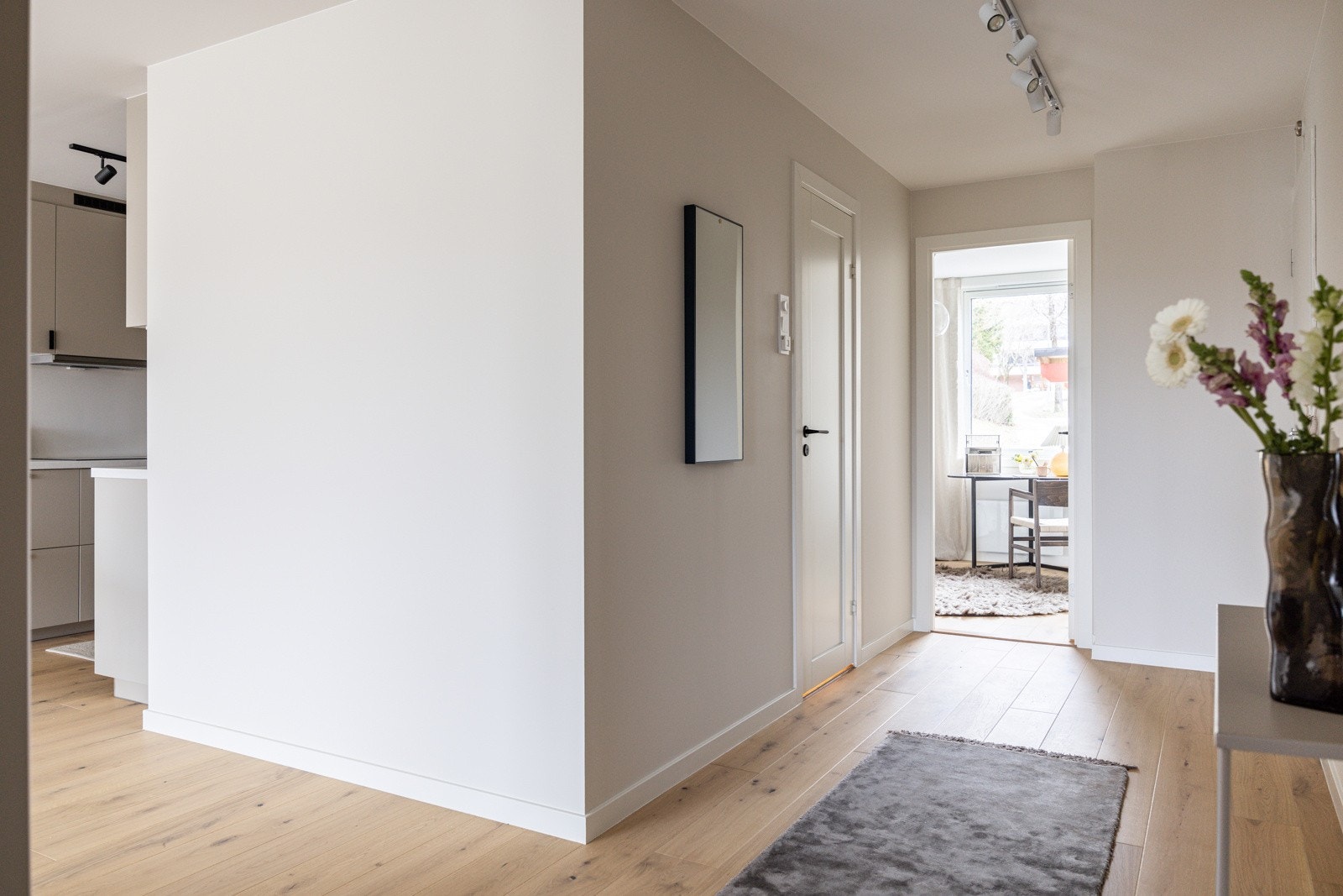Velkommen inn i en lys og innbydende entré med slette, malte vegger i en delikat beigetone og 1-stavs parkett fra 2024. Galleribilde