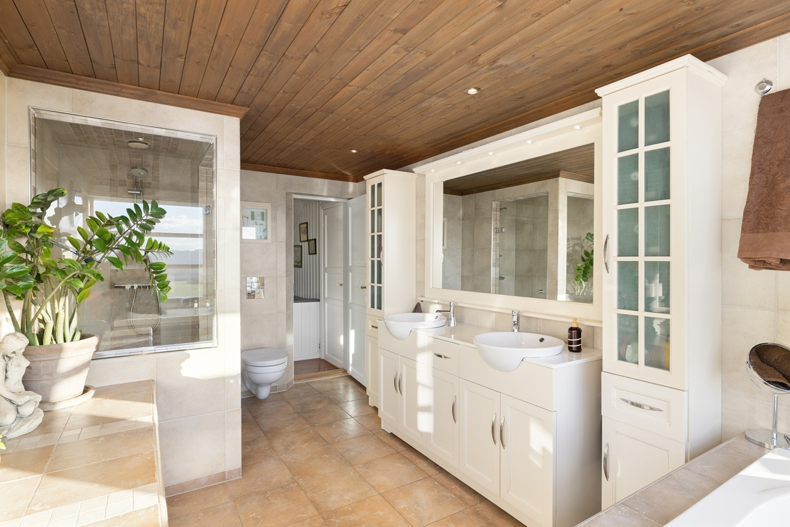 Et flott flislagt bad med underliggende gulvvarme og downlights i himling. Innredningen består av et underskap/ sideskap, dobbel servant, speil, lys og et vannklosett. Galleribilde