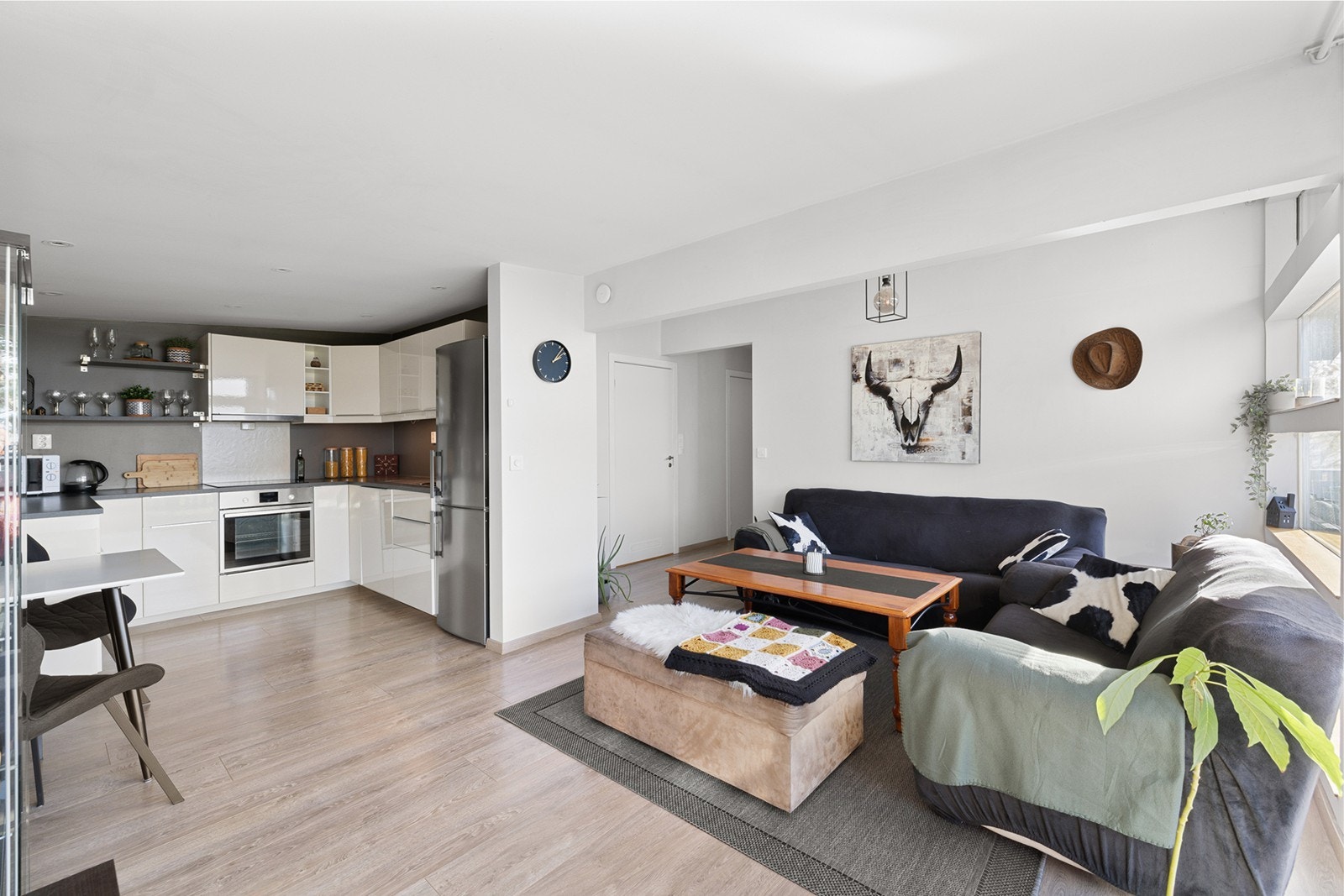 Moderne kjøkkeninnredning med hvite glatte fronter, og med laminert benkeplate med nedfelt oppvaskkum med ett-greps blandebatteri. Integrert oppvaskmaskin, integrert komfyr og nedfelt platetopp og det er tilkoblet en ventilator over kokeplass. Galleribilde