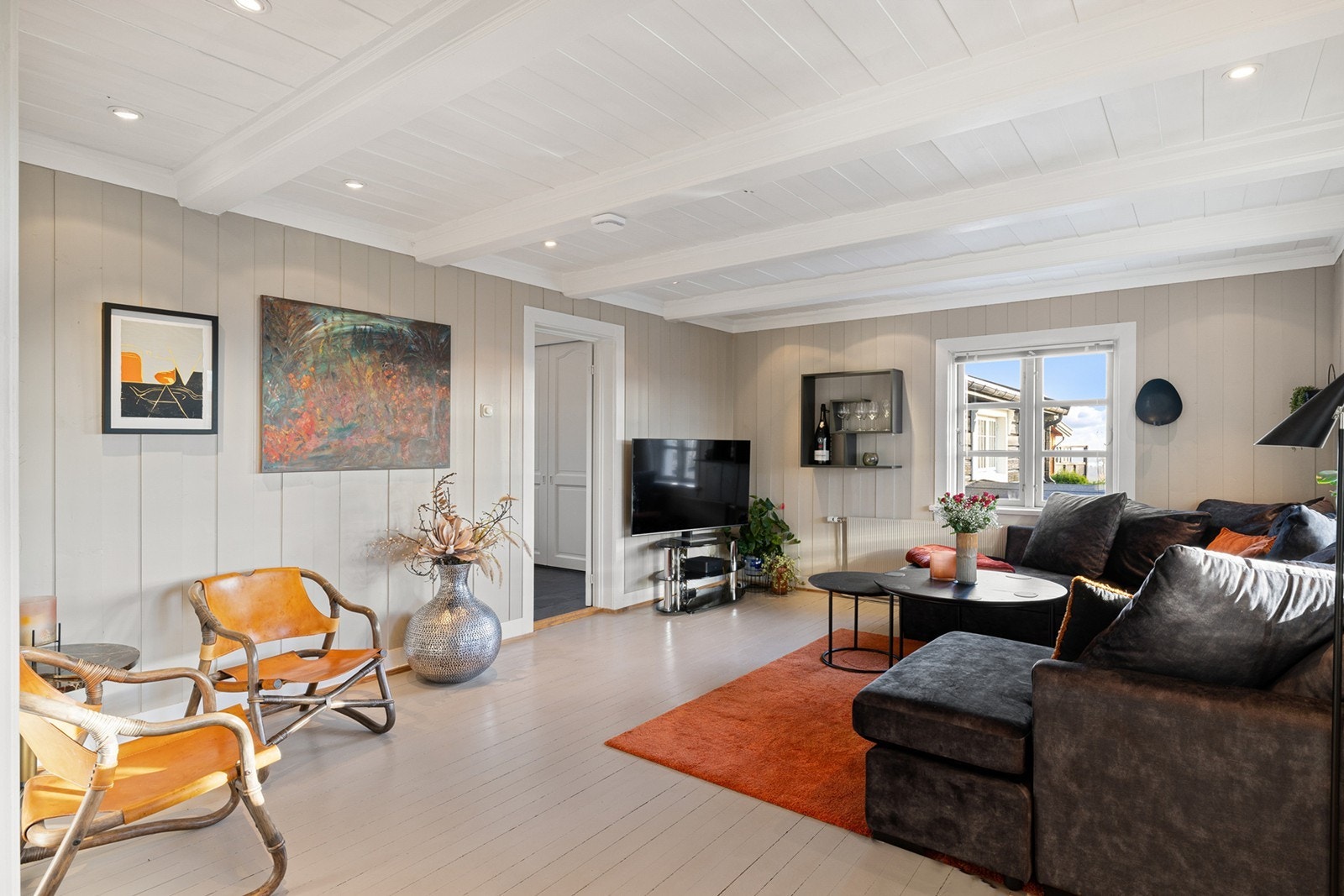 Stuen er enkel å innrede med sofagruppe og tv-møblement. På gulvet er det malt tregulv, malt panel på vegger og i tak og downlights i himling. Galleribilde