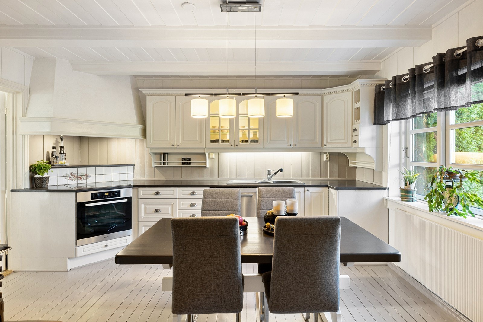 Et hyggelig og innholdsrikt kjøkken med god benkeplass og fin kombinasjon av skuffer og skap for oppbevaring. Flere av skapene har fine glassdører som viser frem serviset, samt gode arbeidsflater for kokken. Galleribilde