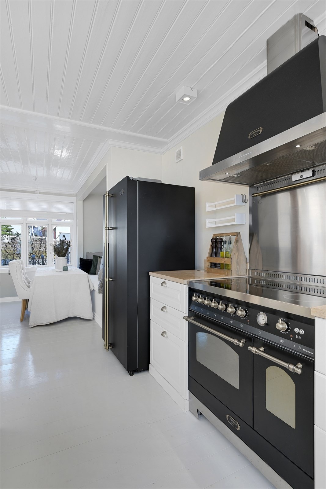 En eksklusiv komfyr med ventilator er plassert på langveggen sammen med et frittstående kjøl-/fryseskap. Galleribilde